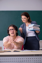 Old female teacher and male student in the classroom