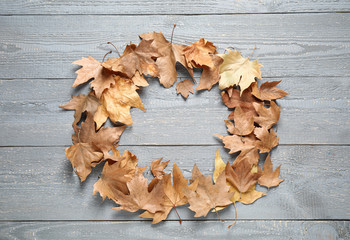 Frame made of autumn leaves on grey wooden background, top view. Space for text