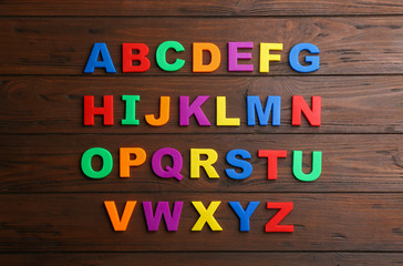 Fototapeta na wymiar Colorful magnetic letters on wooden background, flat lay. Alphabetical order