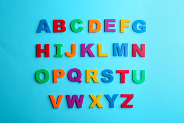 Colorful magnetic letters on blue background, flat lay. Alphabetical order