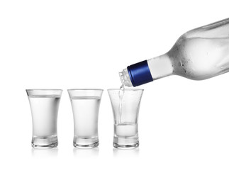 Pouring cold vodka into shot glass on white background