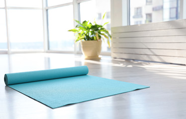 Unrolled light blue yoga mat on floor in room
