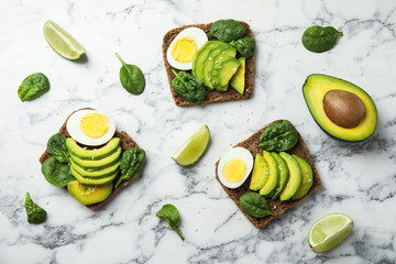 Flat lay composition with avocado toasts on white marble table