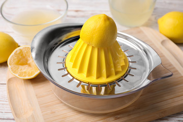 Citrus juicer and squeezed lemon on wooden board