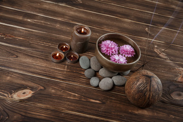 Obraz na płótnie Canvas Singing bowl with candles with pebbles on dark wooden background
