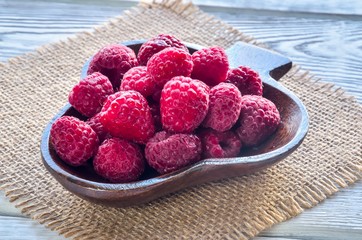 Fresh red fruits. Juicy raspberries in a wooden dish.