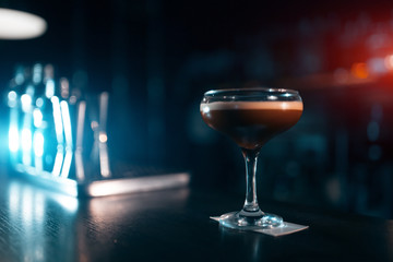 elegant glass with espresso martini cocktail on blue background;