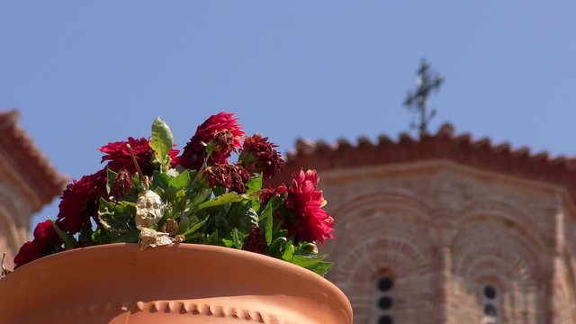 Flowerbed with flowers on the background of the Orthodox chapel. Monasteries in Meteora, Greece.