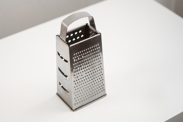 aluminum grater for vegetables on a light background.