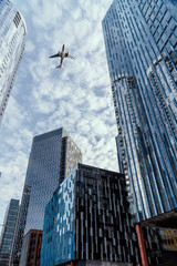 Generic airplane flying over glass skyscrapers