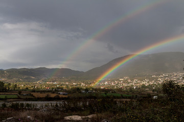 Doppelter Regenbogen über einem kleinen Ort im Gebirge - 297913971