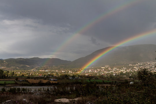 Doppelter Regenbogen über einem kleinen Ort im Gebirge