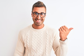 Naklejka premium Young handsome man wearing glasses and winter sweater over isolated background pointing and showing with thumb up to the side with happy face smiling