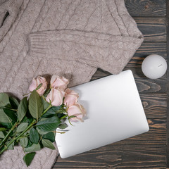beautiful dress with white roses, laptop and candle on wooden background;