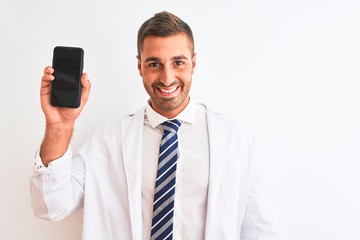 Naklejka premium Young scientist man showing smartphone screen over isolated background with a happy face standing and smiling with a confident smile showing teeth