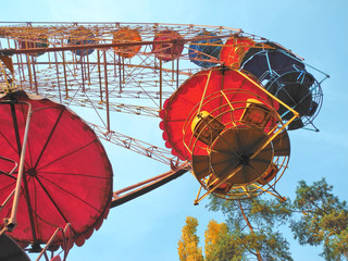 Ferris wheel in city park, bottom view of multicolored cabins        