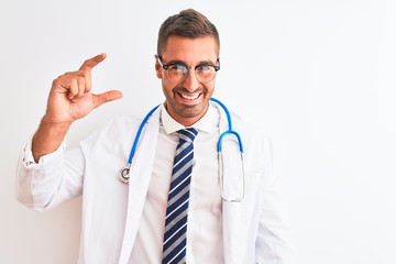 Young handsome doctor man wearing stethoscope over isolated background smiling and confident gesturing with hand doing small size sign with fingers looking and the camera. Measure concept.