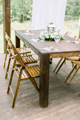 Wedding dinner table decoration outdoors in forest. Wooden table setup for wedding party or dinner reception. Rustic decorations on the table