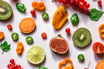 Colorful raw healthy food - slices of fruits and vegetables on white background