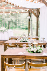 Rustic style wedding wooden decorated tables outdoors. Decorations made of wood, flowers, greenery and served on the festive table
