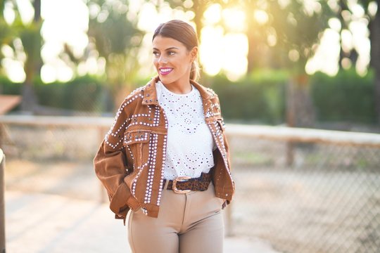 Young beautiful woman wearing jacket smiling happy and confident. Standing with smile on face at the town park