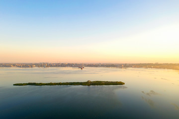 Obraz na płótnie Canvas Dawn at the industrial city with a port and an island in the foreground. Drone photography
