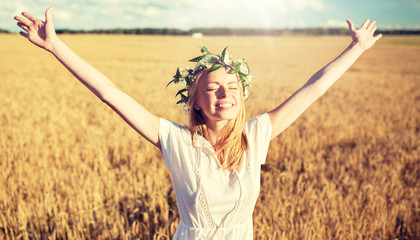 happiness, nature, summer holidays, vacation and people concept - smiling young woman in wreath of flowers and white dress on cereal field