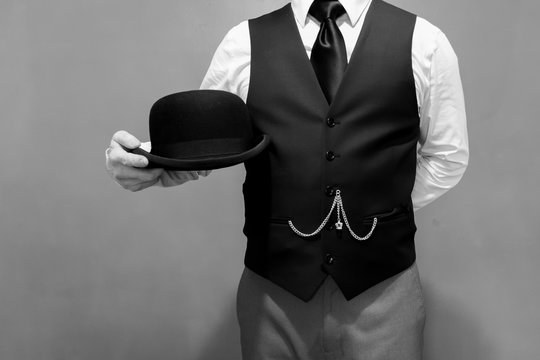 Black and White Portrait of Butler Standing at Attention and Holding a Bowler Hat. Concept of Service Industry and Professional Hospitality. Dependable Servant. Copy Space for Service.