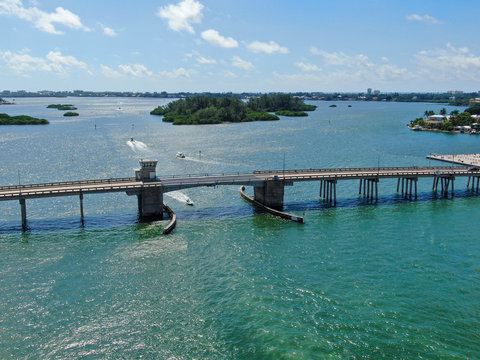 Aerial view of open street bridge crossing ocean with small boat and linking Island Bay and Sarasota, Florida, USA
