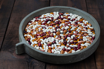 Beans on concrete dish on wooden background