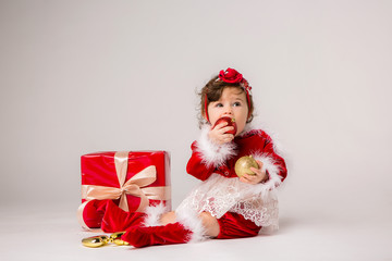 toddler girl Santa with red gift box and Christmas tree toys on white background, space for text