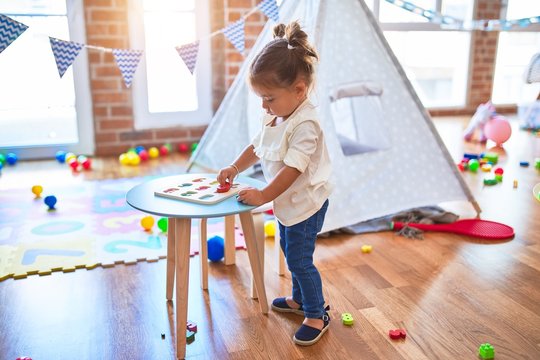 Young beautiful toddler learning mathematics playing with maths game at kindergaten