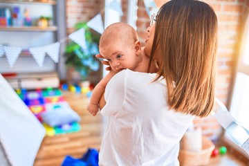 Young beautifull woman and her baby standing at home. Mother holding and hugging newborn