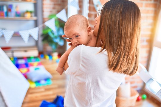 Young beautifull woman and her baby standing at home. Mother holding and hugging newborn