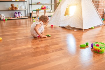 Beautiful caucasian infant playing with toys at colorful playroom. Happy and playful at kindergarten.