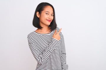 Fototapeta premium Young chinese woman wearing striped t-shirt standing over isolated white background cheerful with a smile of face pointing with hand and finger up to the side with happy and natural expression on face