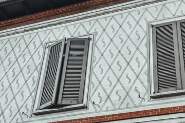 Italian  façade: finely decorated walls and window with blinders in an old, heritage building in a court in Milan.