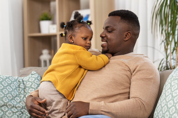 family, fatherhood and people concept - happy african american father with baby daughter at home