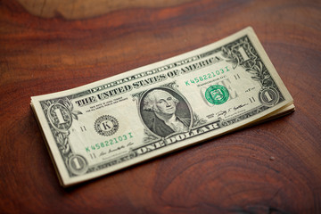 U.S. dollar, American dollar bank notes on natural  wood table texture background, selective focus with shallow depth of field