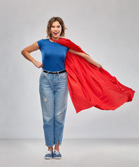 women's power and people concept - happy woman in red superhero cape over grey background