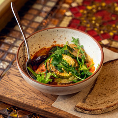 Plate with fork with baked eggplant, tomatoes, arugula leaves and spices. Slice of black bread. Healthy vegetarian menu