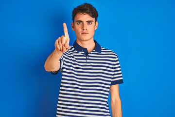 Fototapeta premium Teenager boy wearing casual t-shirt standing over blue isolated background Pointing with finger up and angry expression, showing no gesture
