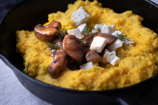Traditional Eastern European corn mush (mamaliga, polenta, banosh, balmes) topped with sheep cheese, mushroom gravy, fried meat pieces