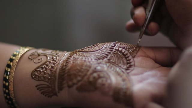 Applying henna to girls hand . The design of the henna can be seen as its shot closeup