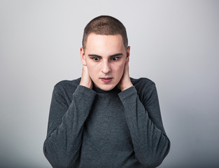 Obraz premium Feared unhappy crying man with shocked face with headache holding the head. Closeup studio portrait on grey background. Negative
