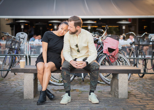 Interracial couple resting on outdoor bench
