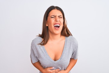 Portrait of beautiful young woman standing over isolated white background with hand on stomach because nausea, painful disease feeling unwell. Ache concept.