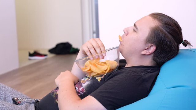 Young Stylish Overloaded Man Eats Chips At Home