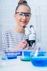 Teen girl student caring out experiments in chemistry class.high school students with microscopes in laboratory. - 297925580