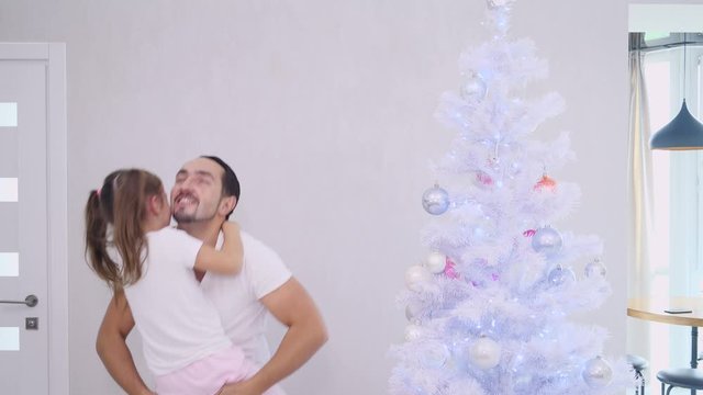 Loving father picking up his cute daughter, she embraces his neck and father strats to turn around, both smiling and looking extremely happy.